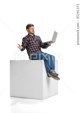 Full-length portrait of man with expression of misunderstanding having business video call on laptop isolated over white background Full-length portrait of man with expression of misunderstanding having business video call on laptop isolated over white background 85291372