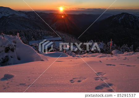 The burning sun set on the horizon and the mountains of the Northern Alps 85291537