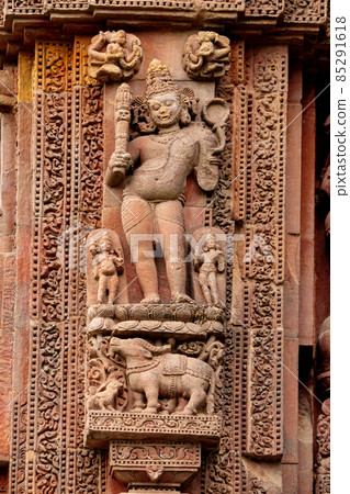 Close-up carved stone sculpture of Lord Yama at Rajarani Temple. 11th century Odisha style temple constructed dull red and yellow sandstone, Bhubaneswar, Odisha, India. Close-up carved stone sculpture of Lord Yama at Rajarani Temple. 11th century Odisha style temple constructed dull red and yellow sandstone, Bhubaneswar, Odisha, India. 85291618