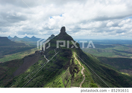 View of stairs and Tungi hill rock, Mangi Tungi, Nashik, Maharashtra, India. Prominent twin-pinnacled peak with plateau in between. View of stairs and Tungi hill rock, Mangi Tungi, Nashik, Maharashtra, India. Prominent twin-pinnacled peak with plateau in between. 85291631