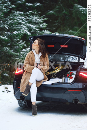 Tired driver woman stopped her car in winter forest to give herself rest and to drink a cup of coffee 85293201