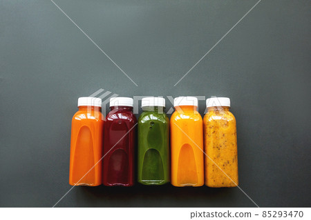 Fresh juices or cocktails of fruits and vegetables in bottles on a gray background.  85293470