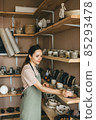 Woman sells handmade pottery in store. 85293478