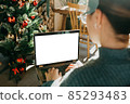 A young beautiful European woman uses her laptop in a Christmas festive atmosphere. Place for text, close-up screen 85293483