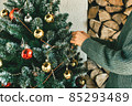 A woman decorates a Christmas tree at home.  85293489