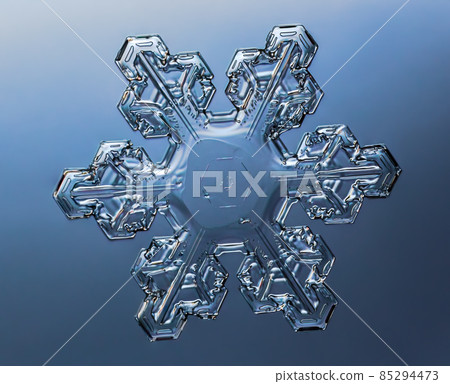 Snowflake on smooth gradient background. Macro photo of real snow crystal on glass surface. This is small snowflake with unusual pattern. Snowflake on smooth gradient background. Macro photo of real snow crystal on glass surface. This is small snowflake with unusual pattern. 85294473