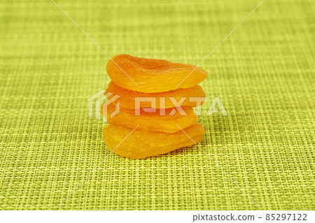 Dried apricots stacked on a green background Dried apricots stacked on a green background 85297122