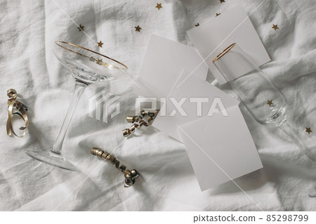 Happy New Year composition. Blank note pads mockups scene. Champagne glasses with golden confetti stars. White wrinkled linen table cloth background. Celebration, party concept. Flat lay, top view. 85298799