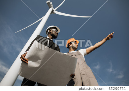 Inspector and engineer talking on field with wind turbines Inspector and engineer talking on field with wind turbines 85299731