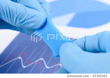 Blue porous foam like material stretched in scientist hands in laboratory 85300365