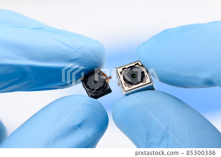 Two cell phone camera modules in scientist hands. Two cell phone camera modules in scientist hands. 85300386