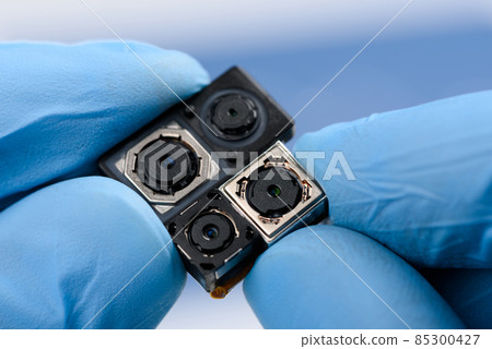 Smartphone camera modules in scientist hands. Different sensor sizes and technology used. 85300427