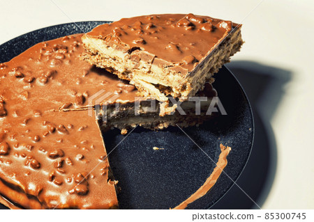 Swedish almond and chocolate cake with a slice cut off, with filling and nuts 85300745