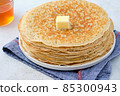 Crepes, thin pancakes with honey and butter on a white plate. Close up. 85300943
