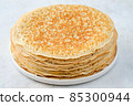 Crepes, thin pancakes with honey and butter on a white plate. Close up. 85300944
