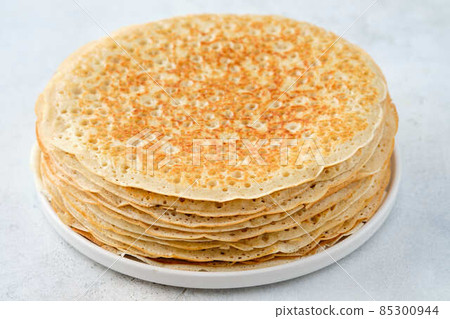 Crepes, thin pancakes with honey and butter on a white plate. Close up. 85300944