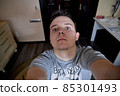 A young man makes a self-portrait indoors at home 85301493