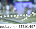 Abstraction with glare and reflection of lights and people. Blurred office green background, illuminated interior with flickering bokeh lights, modern illuminated business hall 85301497