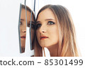 Portrait of a beautiful young woman looking into the mirror 85301499