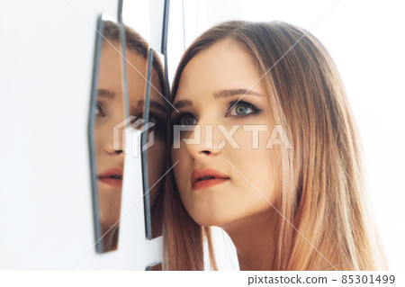 Portrait of a beautiful young woman looking into the mirror Portrait of a beautiful young woman looking into the mirror 85301499