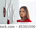 Portrait of a beautiful young woman looking into the mirror 85301500