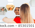Portrait of a beautiful young woman looking into the mirror 85301501