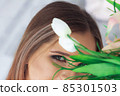 A beautiful woman's face behind a flowers. 85301503