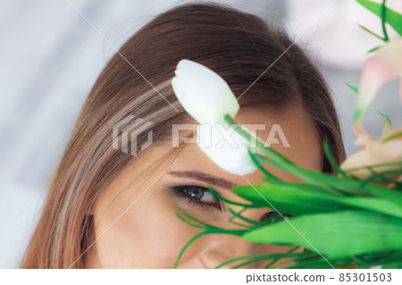 A beautiful woman's face behind a flowers. A beautiful woman's face behind a flowers. 85301503