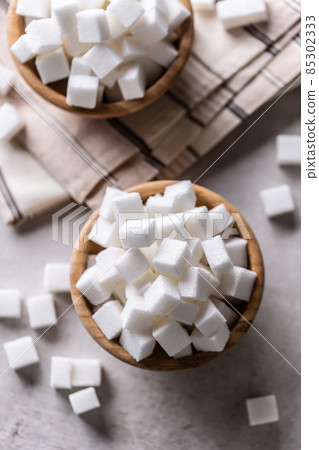 White sugar cubes in a wooden bowl on the table 85302333