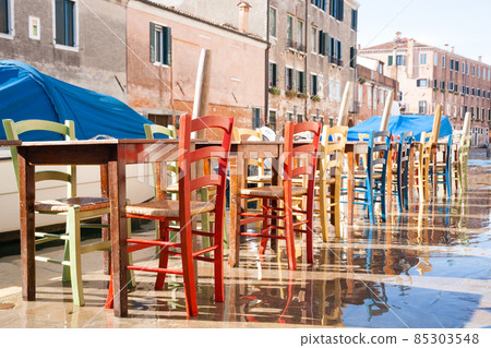 Colorful chairs in a row along Venetian canal 85303548