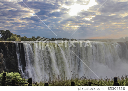 Beautiful cloudy landscape with morning sun rays over Victoria Falls. 85304838