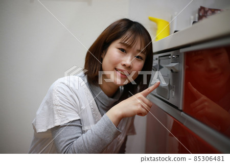 A woman pointing at the child lock on the stove 85306481