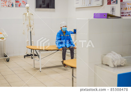 Boy playing doctor in doctor's uniform in hospital interior 85308478
