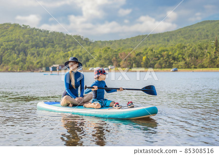 happy family of two, mother and son, enjoying stand up paddling during summer vacation happy family of two, mother and son, enjoying stand up paddling during summer vacation 85308516