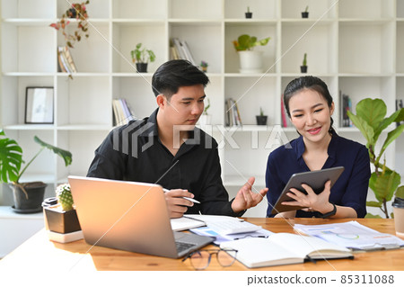 Two young business colleagues using digital tablet and discussing project together. 85311088