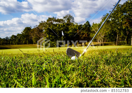Golf clubs and golf balls on a green lawn in a beautiful golf course with morning sunshine. golf ball on green grass ready to hit on golf course background 85312783