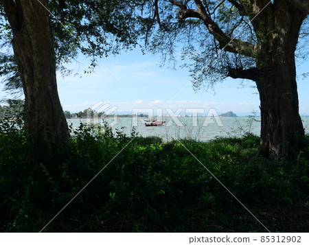 Trawler and Fishing boat at sea with mountain with city and island at Prachuap Bay with two trees silhouette in the foreground, Prachuap Khiri Khan, Thailand Trawler and Fishing boat at sea with mountain with city and island at Prachuap Bay with two trees silhouette in the foreground, Prachuap Khiri Khan, Thailand 85312902