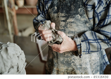 Close-up of senior man holding clay in his hands and making earthenware dishes in creative studio 85316430