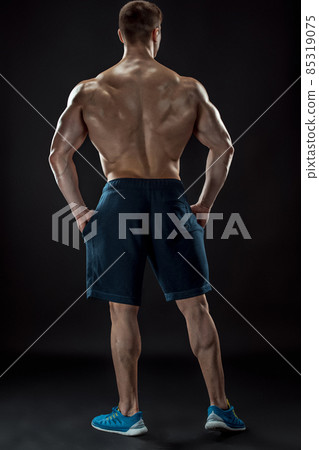 Muscular bodybuilder guy doing posing over black background Muscular bodybuilder guy doing posing over black background 85319075