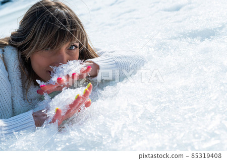 Close-up portrait of a caucasian woman lying on the snow. Close-up portrait of a caucasian woman lying on the snow. 85319408