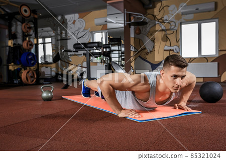 Young man doing exercises in the gym Young man doing exercises in the gym 85321024