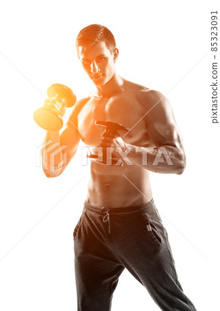 Athletic man showing muscular body and doing exercises with dumbbells Athletic man showing muscular body and doing exercises with dumbbells 85323091
