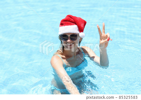 Young smiling woman in santa claus hat in pool 85325583