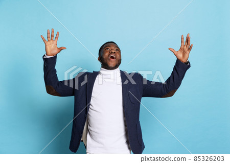 Portrait of young stylish excited man, student wearing white neck-polo and jacket isolated on navy color background. 85326203