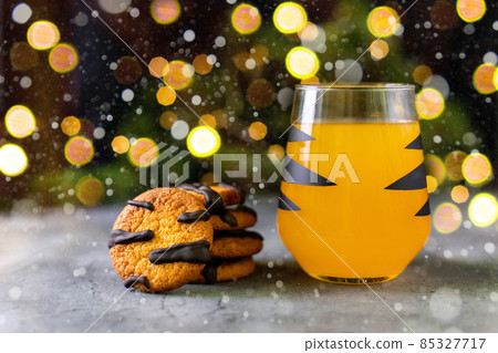 orange mandarin cocktail in glass with black stripes and cookies. Christmas holiday drink. Concept for children new year 85327717