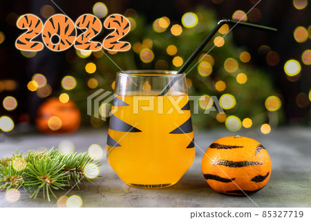 orange mandarin cocktail in glass with black stripes. Christmas holiday welcome drink. Concept for children new year orange mandarin cocktail in glass with black stripes. Christmas holiday welcome drink. Concept for children new year 85327719