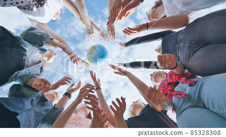 Female student girls standing in a circle toss the world globe up. 85328308