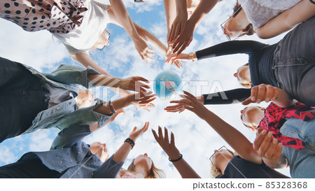 Female student girls standing in a circle toss the world globe up. 85328368