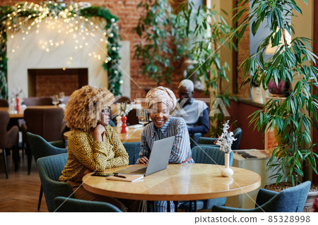 Two African women using laptop in their work during meeting in cafe, they smiling and discussing online work 85328998