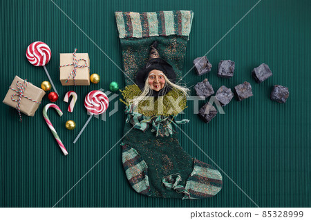 Befana sock with sweet coal and candy on dark greeen background. Italian Epiphany day tradition. 85328999